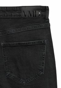 Dos d'un jean en denim noir montrant une seule poche et une étiquette en cuir noir avec le logo "VMD" embossé sur la ceinture.