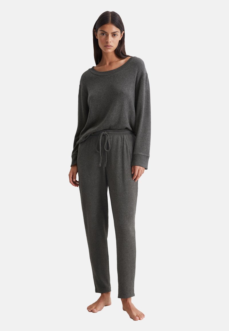 Grijze, zachte lounge set met een crew neck lange mouw top en broek met trekkoord taille en geribde boorden. Minimalistisch ontwerp, relaxte pasvorm.