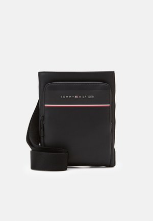 Czarna torba na ramię z przednią kieszenią na suwak, logo Tommy Hilfiger i detalem w postaci czerwono-biało-niebieskich pasków, z regulowanym paskiem na ramię.