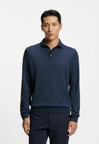 Mörkblå långärmad polo med strukturerad yta, med krage och tre knappar, kombinerad med mörka byxor.