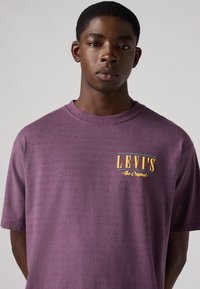 Paarse gestreepte korte mouwen t-shirt van katoen met een ronde hals. Bevat een gele Levi's logo op de linkerkant van de borst.