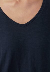 V-Ausschnitt T-Shirt in dunklem Marineblau, aus einem weichen, strukturierten Stoff mit subtilen horizontalen Linien. Verfügt über ein klares, schlichtes Ausschnittdesign.