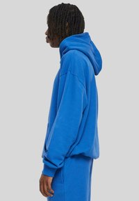 Blauwe hooded sweatshirt van een katoenmix, met een ontspannen pasvorm, verlaagde schouders en ribgebreide manchetten. Vlotte textuur en casual ontwerp.