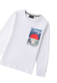 T-shirt bianco a maniche lunghe con un vivace patch grafico che presenta le scritte "Change" e "Horizon", foglie di palma e un sole rosso su uno sfondo blu.