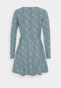 Grön långärmad klänning med ett vitt blommönster, figurnära midja, utsvängd kjol och detaljer med dragkedja i ryggen. Mjuk tyg med en slät yta.