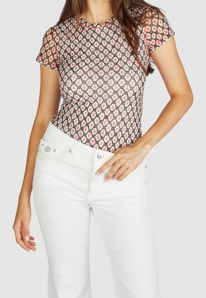 Body transparent à manches courtes avec un motif géométrique en rose et noir. Associé à un jean en denim blanc avec des éléments décoratifs.