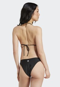 Černý bikiny s mašlí za krkem a nízkým pasem. Obsahují bílý logotyp na zadní straně. Hladký, elastický materiál.