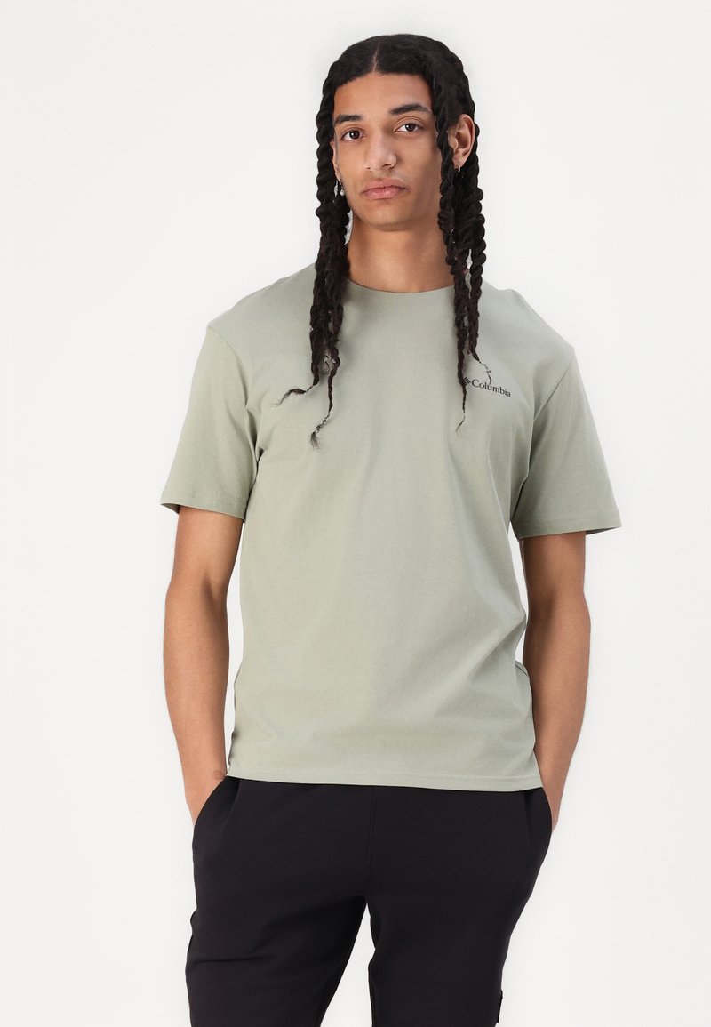 Camiseta de manga corta verde claro hecha de algodón, con cuello redondo y un pequeño logo en el lado izquierdo del pecho. Textura suave y ajuste casual.