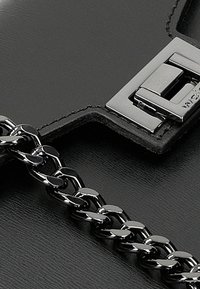 Borsa in pelle nera con chiusura in metallo lucido e tracolla a catena, che mette in risalto la texture liscia e gli elementi di design minimalisti.