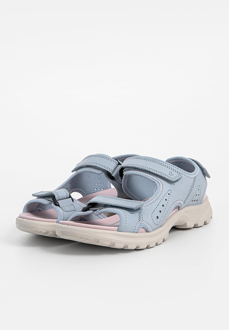 Helleblaue synthetische Sandalen mit geschlossener Zehenpartie, verstellbaren Klettverschlüssen und einer strukturierten Gummisohle. Mit pinken Akzenten versehen.