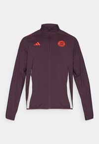 Bordeaux treningjakke med høy krage, lange ermer, hvite sidepaneler og røde detaljer, med et emblem på brystet og Adidas-logo.