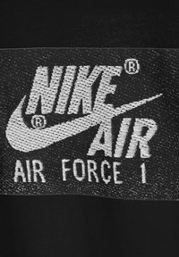 Zwart stoffen patch met witte geborduurde tekst: "NIKE AIR AIR FORCE 1" met het Nike-logo en het geregistreerde handelsmerk symbool.