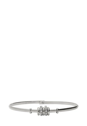 Silver bangle with three circular bead accents, two adorned with clear gemstones. Smooth texture, minimalist design, and oval shape.