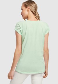 Mintgrøn kortærmet t-shirt med opfoldede ærmer, blød tekstur, afslappet pasform og rund udskæring, vist fra ryggen.