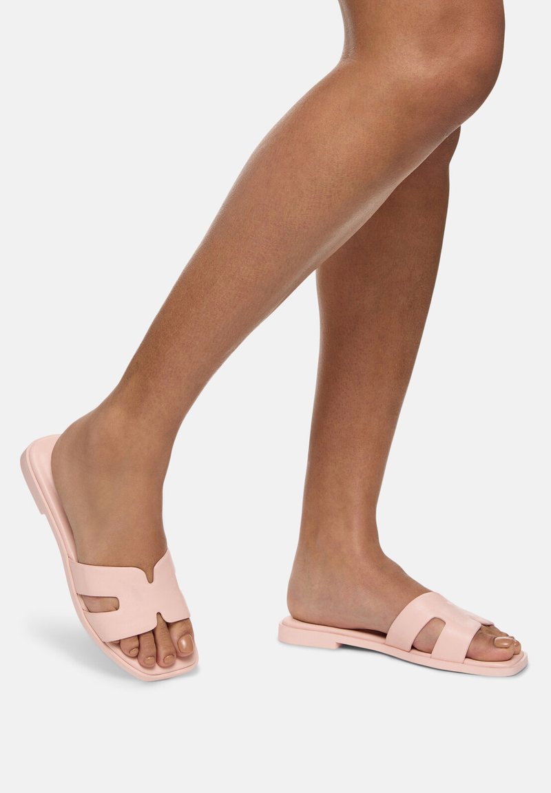 Sandales à glissière roses en matériau lisse, avec deux bandes horizontales et un design ouvert à l'avant. La semelle est plate et légèrement surélevée.