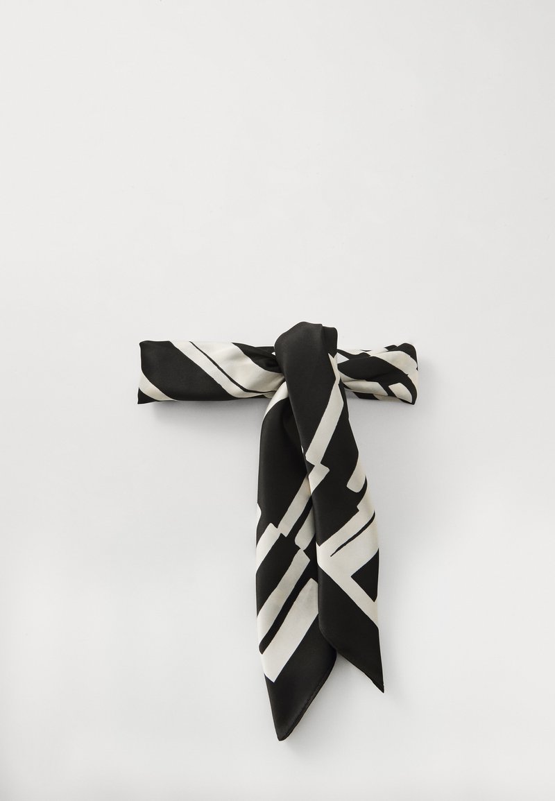 Czarny jedwabny szalik zdobiony ząbkowanym białym wzorem geometrycznym, związany w supeł na środku, o gładkiej, błyszczącej fakturze.