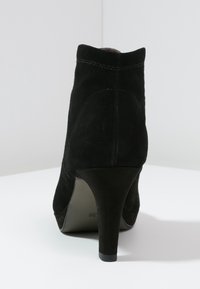 Botas de tobillo de ante negro con una forma elegante, tacón de aguja alto y detalles de costura en contraste a lo largo de la costura trasera.