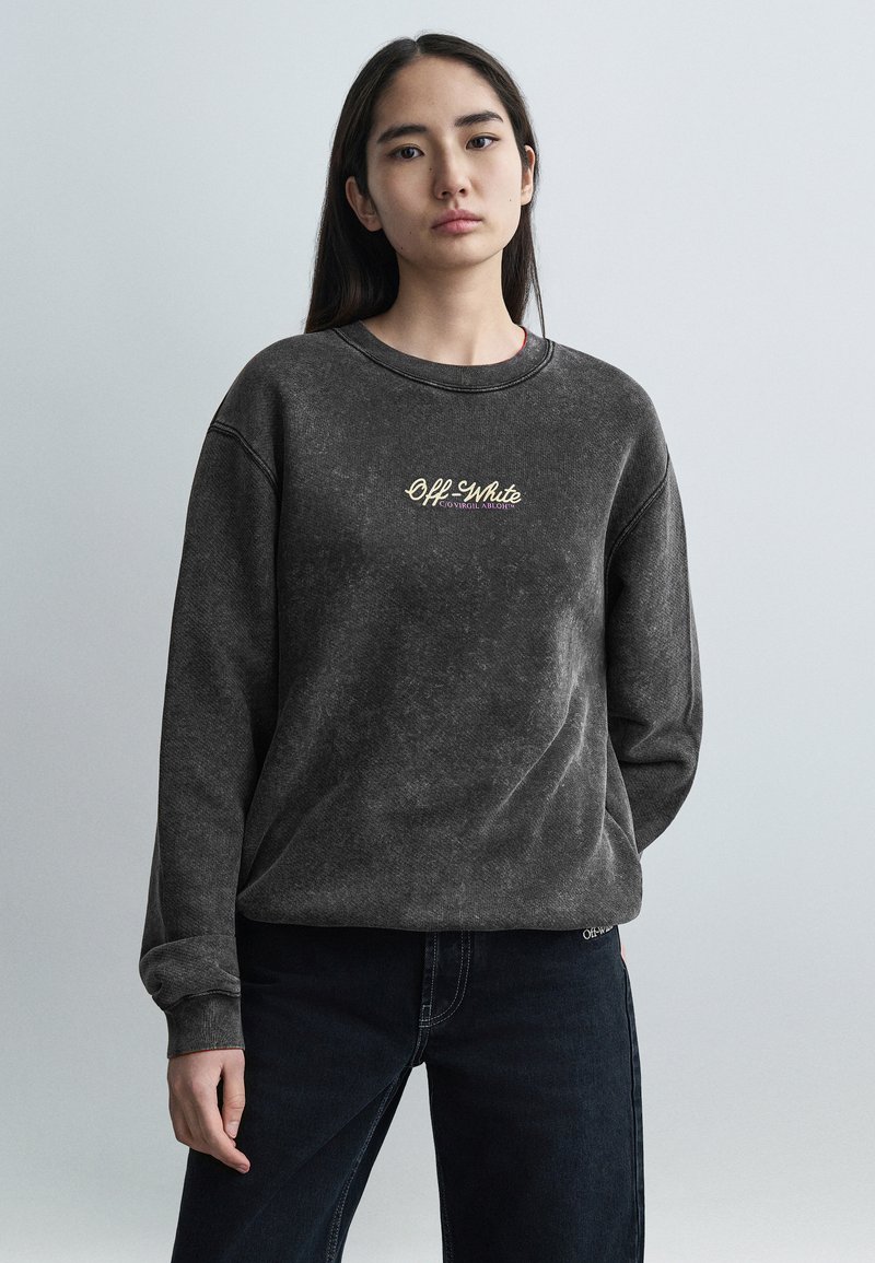 Σκούρο γκρι φλις φούτερ με στρογγυ λή λαιμόκοψη, διακοσμημένο με χρυσό λογότυπο "Off-White". Μακριά μανίκια με ριμπ τελειώματα, σε συνδυασμό με σκούρο τζιν.