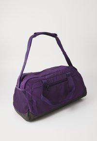 Lilla duffelveske med svart bunn, laget av stoffmateriale, med doble bæreremmer, frontlomme med glidelås og mesh-sider for ventilasjon.