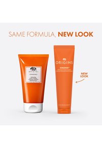 To oransje tuber med Origins Ginzing ansiktsrens; den ene har hvit kork og etikett, den andre er ensfarget uten etikett.