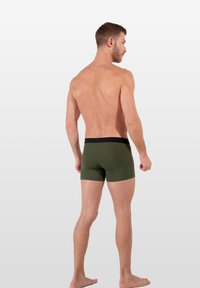 Green men's boxer briefs with a black waistband, form-fitting design, and smooth fabric texture, shown from a side and back view.
