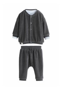 Hall griibitud puuvillase kostüümi, mis sobib nii meestele kui naistele. Kompositsioon sisaldab nööpidega jakki, mille mansetid on elastsed, ja samasuguseid elastse vöökohtaga pükse, millel on pael.