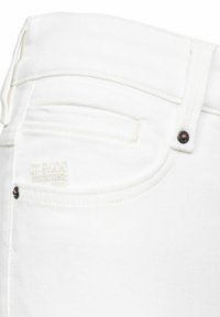 Jeans de denim blanco con un fit ajustado, con un bolsillo cosido y un parche con el logo de G-Star Originals cerca del bolsillo trasero, y herrajes en tono cobre.