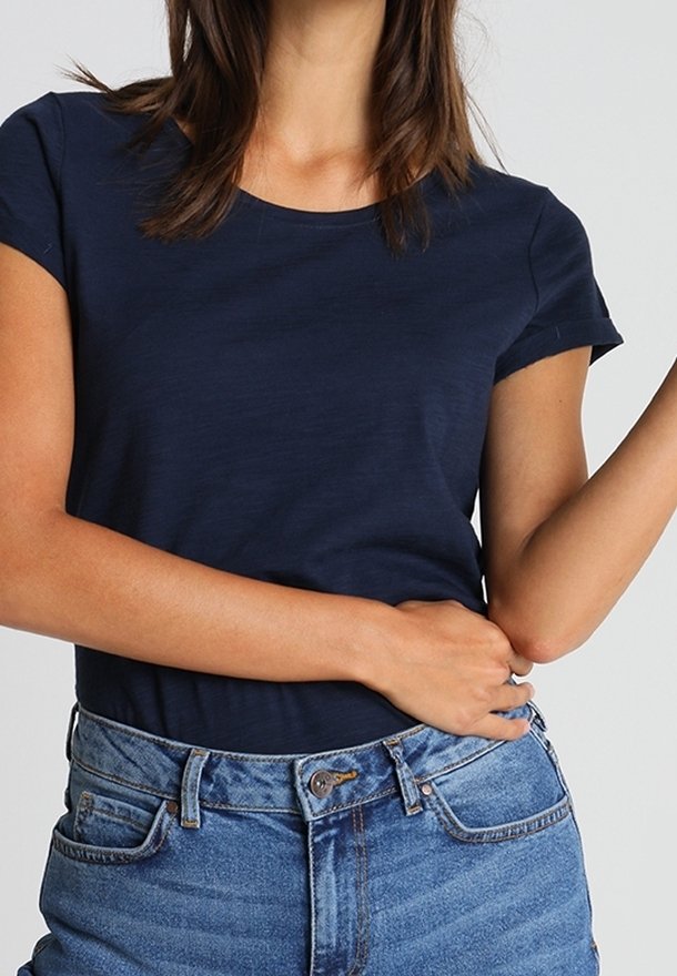 Granatowy t-shirt z krótkim rękawem i okrągłym dekoltem, wykonany z miękkiej tkaniny; zestawiony z jasnoniebieskimi dżinsami z wysokim stanem.