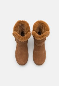Bottines en daim marron avec une doublure en fourrure douce autour du bord, bout rond et semelle plate. Design simple sans quincaillerie visible.
