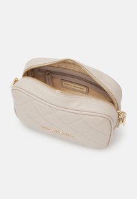 Beige quilted leather bag with a gold zip closure. Interior features a zip pocket and a tag labeled "MARIO VALENTINO." Smooth texture.