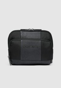 Schwarze rechteckige Tasche aus einer Mischung aus glattem Leder und strukturierten Mesh-Paneelen, mit einem Reißverschluss und eingeprägtem Logo auf der Vorderseite.