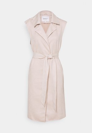 Gabardina sin mangas beige con cuello, cintura ceñida con cinturón y bolsillos laterales, confeccionada en un material suave similar a la ante. Textura lisa, diseño minimalista.