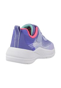 Zapatilla deportiva morada con parte superior texturizada, suela blanca y acentos contrastantes en rosa y azul. Cuenta con una lengüeta en el talón para facilitar el calzado.