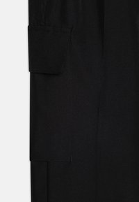 Tecido preto que exibe uma textura lisa com um bolso dobrado. O design apresenta linhas limpas e detalhes de costura mínimos.