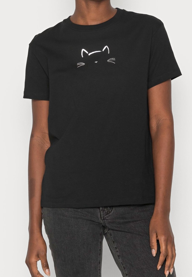 Camiseta de algodón negra con un contorno blanco de la cara de un gato en el pecho. Diseño clásico de cuello redondo con mangas cortas.