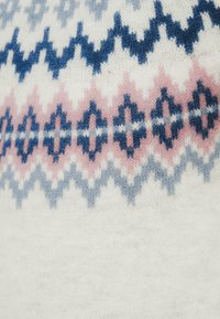 Πλεκτό πουλόβερ με κρέμ φόντο και γεωμετρικά σχέδια σε μπλε, ροζ και γκρι χρώματα· μαλακή υφή με άνετο σχεδιασμό.