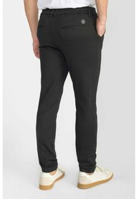 Pantalons ajustés noirs en tissu texturé, avec des poches arrière, des passants de ceinture et un petit logo sur la poche droite.