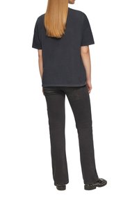 Zwarte katoenen T-shirt met een ontspannen pasvorm, korte mouwen en een ronde halslijn, gecombineerd met zwarte flared broek en versierde zwarte schoenen.