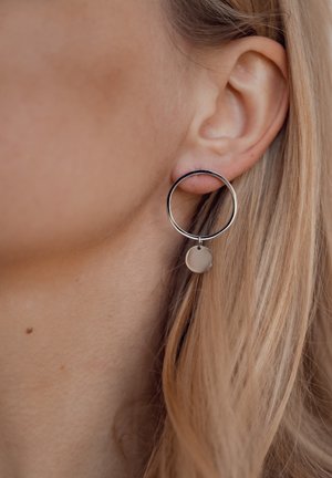 Silberne Creolen mit einem runden Charm. Der Ring ist dünn und poliert, mit einem glatten, minimalistischen Design.