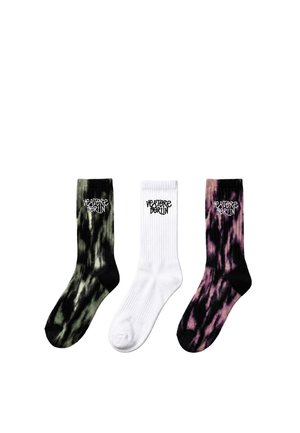 Three crew-length socks side by side, two tie-dye in black-green and black-purple, one solid white, all with "VERTERE BERLIN" text on the cuff.