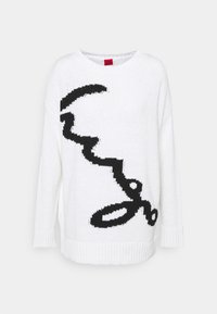 Maglione bianco lavorato a maglia con un motivo astratto nero. Presenta un colletto rotondo e polsini e orlo a coste. Tessuto morbido e vestibilità rilassata.