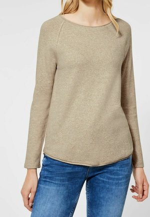 Beige långärmad topp med rundad halsringning och raglanärmar, tillverkad av ett mjukt tyg med en subtil textur och böjd fåll.