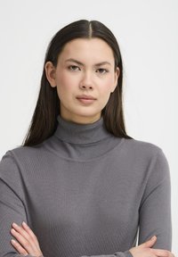 Pelēks augstu kaklu džemperis, viegla adīta auduma, pielāgota piegriezuma, garas piedurknes, ribota apkakle un aproces, gluda faktūra, minimālais dekors.