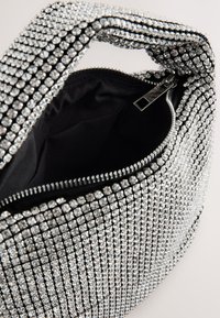 Silver rhinestone-embellished handbag with a black interior, featuring a zippered top opening and a structured shape.