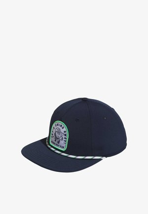 Gorra azul marino hecha de tela con visera plana. Presenta un parche circular con un diseño de un golfista y acentos en verde, además de un ribete estampado.