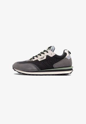 Szare i czarne niskie trampki z zamszowymi i materiałowymi panelami, czarnymi sznurowadłami oraz podeszwą z zielonym akcentem, pokazane z profilu na białym tle.