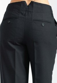 Pantaloni neri su misura con vita aderente, due tasche posteriori e tessuto leggermente strutturato. Design pulito con accenti minimalisti.