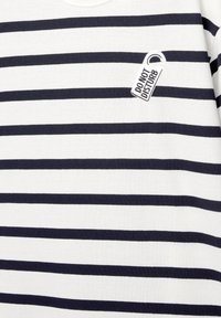 Gestreept shirt met marineblauwe en witte horizontale strepen, ronde halslijn en klein wit "NIET STOREN" label genaaid op de borst.