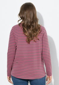 Långärmad skjorta i brunt med rosa horisontella ränder. Mjuk tyg med rundad nederkant och sidofickor, ihop med mörkblå jeans.