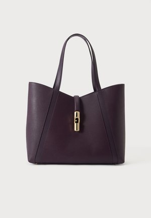 Sac cabas en cuir violet foncé avec deux longues anses et une fermeture centrale dorée sur fond uni.
